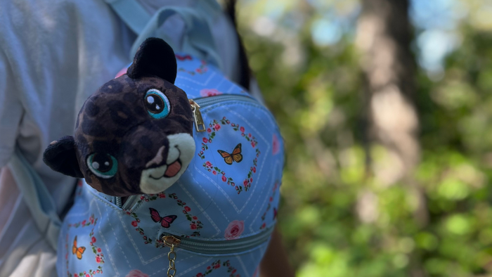 supportive little buddy - the black leopard - in a bag with trees in the background